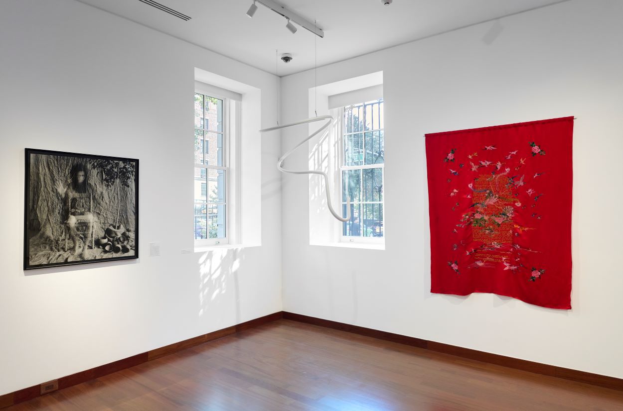 Installation view of the gallery with two art pieces on the walls and one hanging from the ceiling