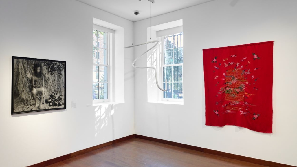Installation view of the gallery with two art pieces on the walls and one hanging from the ceiling